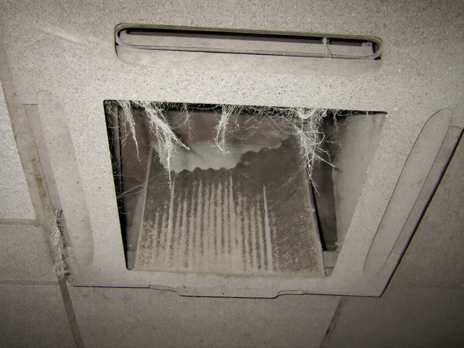 Ceiling AC grille and duct opening covered in dust and lint before cleaning